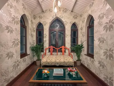 a bedroom with a bed and a table and windows at The Humming Bird A Stay Chapter in Ooty