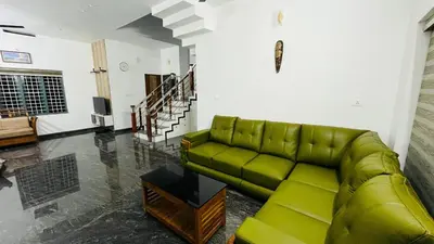 a living room with a green couch and stairs at Dutch Heaven - Luxury Rental Villa Near Cochin Airport in Nedumbassery