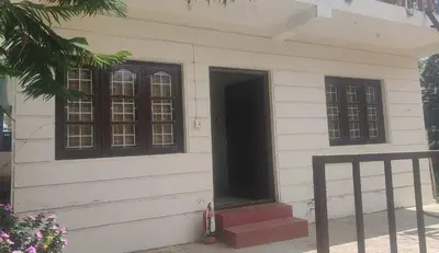 a white house with a black door and windows at GEM Stays in Ooty