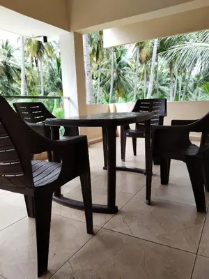 a black table and chairs in a room with palm trees at Limra Farm House in Pollāchi