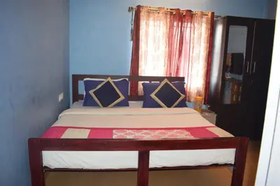 a bedroom with a bed with blue walls and a window at Mass villa in Ooty