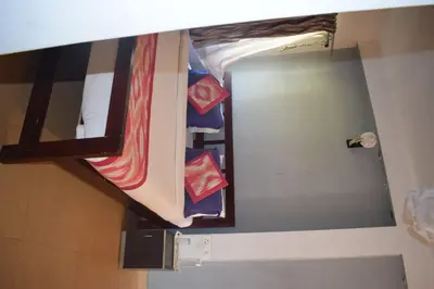ajar view of a room with a bed and a mirror at Mass villa in Ooty