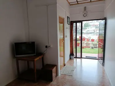 a living room with a television on a table and a door at Trilan Cottages - Donnington Road in Kotagiri
