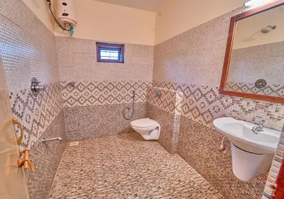 a tiled bathroom with a toilet and a sink at Ushasree Wayanad Premium Pool Resort by VOYE HOMES in Ambalavayal