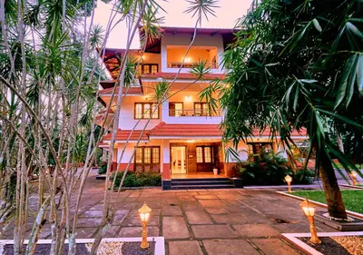 a building with palm trees in front of it at Ushasree Wayanad Premium Pool Resort by VOYE HOMES in Ambalavayal