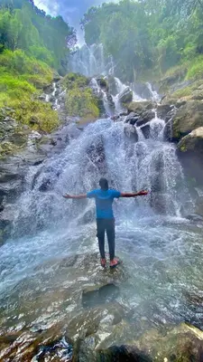 a person standing in front of a waterfall at Coorg Naladi holidays in Kakkabe
