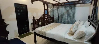 a bedroom with a wooden bed with white sheets and pillows at PADIKKAL BUNGLOW in Vayittiri