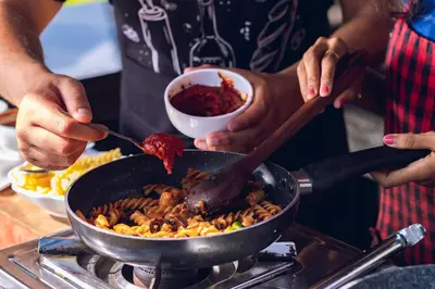 a person cooking food in a pan on a stove at Avana Resort in Mettuppālaiyam