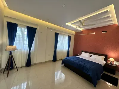a bedroom with a bed with blue sheets and blue curtains at Aalayam, Villament & private pool in Mysore