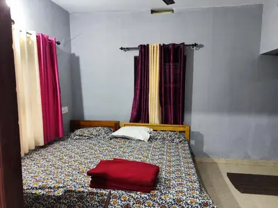 a bedroom with a bed with a red bag on it at Brahmagiri Homestay Serviced Villa in Thirunelli