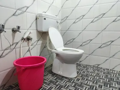 a bathroom with a toilet and a pink bucket at Brahmagiri Homestay Serviced Villa in Thirunelli