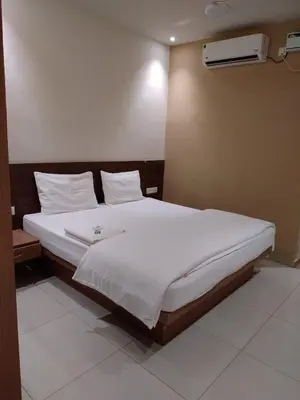 a bed with white sheets and pillows in a room at Sri bhavan residency in Palakkad