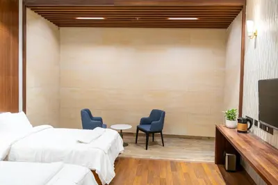 a bedroom with two beds and two chairs and a tv at 0484 Aero Lounge-Terminal 2 Cochin Airport Hotel in Nedumbassery