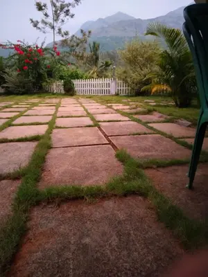 a stone walkway with a bench in a yard at Padikkal Bungalow in Vayittiri