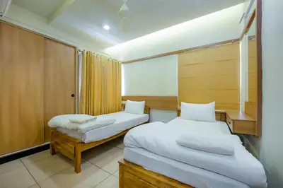 a small room with two beds and a window at Focuz Habitat Hotel And Ayurveda in Malappuram