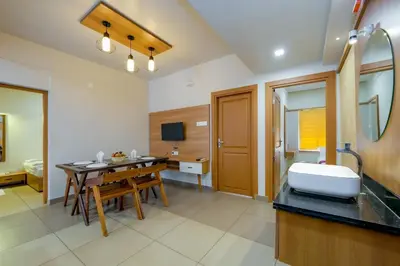 a room with a desk and a kitchen with a table at Focuz Habitat Hotel And Ayurveda in Malappuram
