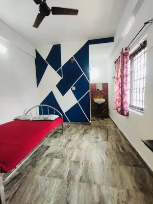 a bedroom with a red bed and a blue and white wall at Omega Tourist Home in Trichūr