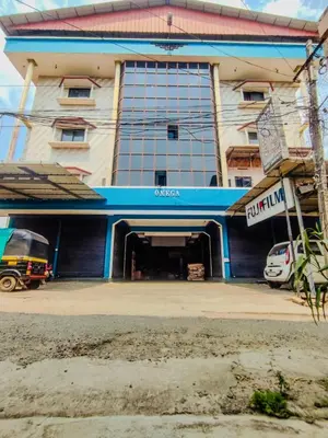 a large building with a parking garage in front of it at Omega Tourist Home in Trichūr