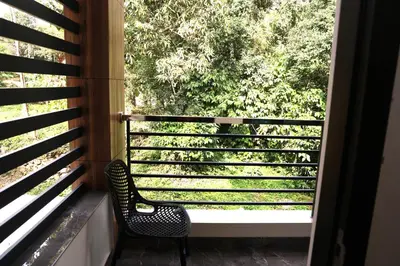 a chair sitting on a balcony looking out a window at Ecostay inn in Sultan Bathery