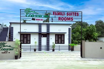 a white building with a sign in front of it at Ecostay inn in Sultan Bathery