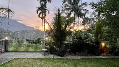 a backyard with a bench and palm trees and a mountain at Hill View Heights Wayanad in Meppādi