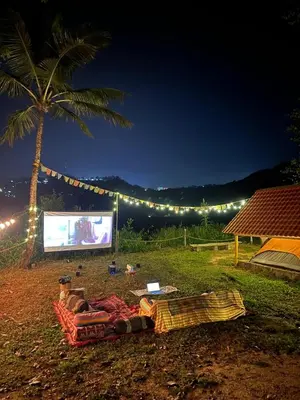 a couch laying on the grass under a palm tree with a screen at TauSco Homestay & Campsite - Coorg in Madikeri