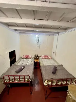 a room with two beds and a table in it at TauSco Homestay & Campsite - Coorg in Madikeri