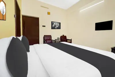 a bedroom with a bed and two chairs and a television at Super Hotel O Thrissur Near Thrissur Medical College in Trichūr