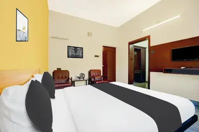 a bedroom with a white bed and a tv at Super Hotel O Thrissur Near Thrissur Medical College in Trichūr