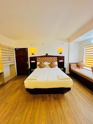 a large bedroom with a large bed and a couch at Kanavu Valley View in Ooty
