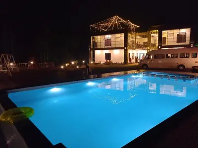 a large swimming pool with blue lighting in front of a building at Mountain Wings Resort in Vythiri