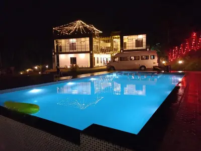 a swimming pool at night with a building with lights at Mountain Wings Resort in Vythiri