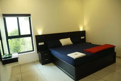 a bedroom with a black bed and a window at Mountain Wings Resort in Vythiri