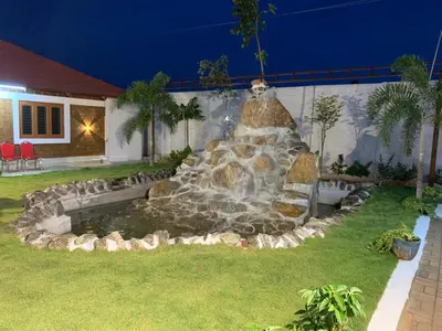 a fountain in the yard of a house at night at Love Green Resorts in Palladam