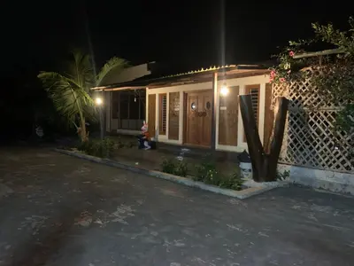 a small house with a child sitting outside at night at Love Green Resorts in Palladam