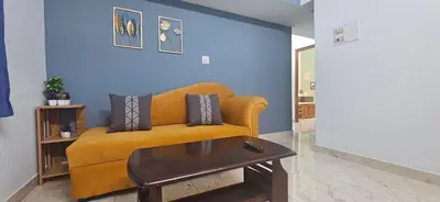 a living room with a yellow couch and a table at SHIs Aathira 2bhk Heart of Coimbatore in Coimbatore
