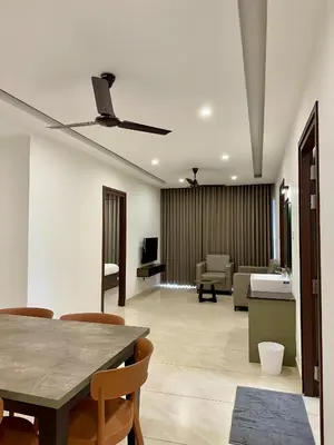 a living room with a ceiling fan and a table at Portico Service Apartments in Kozhikode