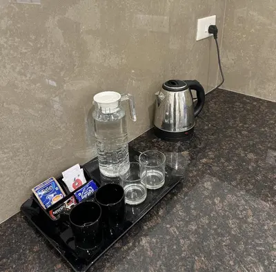 a tray with glasses and a water pitcher and a kettle at Portico Service Apartments in Kozhikode