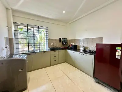 a large kitchen with white cabinets and a red refrigerator at Portico Service Apartments in Kozhikode