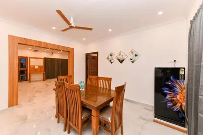 a dining room with a table and chairs and a refrigerator at Hotel Shine International in Mysore