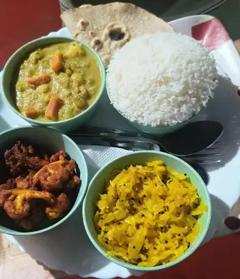 a plate with bowls of food and rice on a table at Perch Next door in Kannur