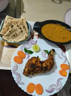 a plate with a piece of meat and a pan of food at Perch Next door in Kannur