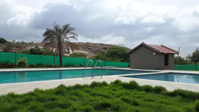 a swimming pool with a green fence around it at Valley Vibes in Rāmanagaram