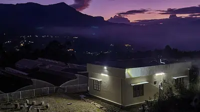 a building with a mountain in the background at night at Home stay in Kanthalloor