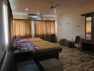 a bedroom with a bed and a couch and a tv at Konar Mandabam in Palani