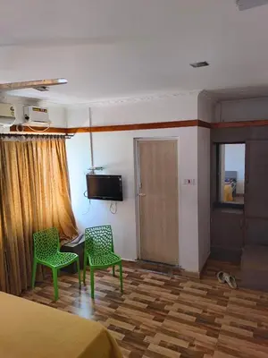 a bedroom with two chairs and a desk and a television at Konar Mandabam in Palani