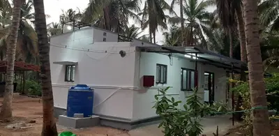 a white house with a blue barrel in front of it at Hotel Rams in Coimbatore