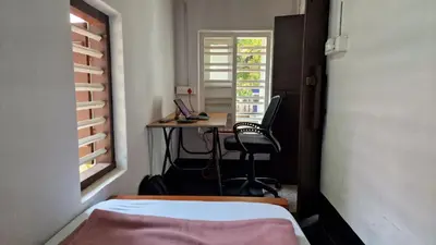 a bedroom with a bed and a desk with a computer at Koodapuzha House Chalakudy in Kizhake Chālakudi