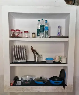 a shelf with bowls and bottles of water at Koodapuzha House Chalakudy in Kizhake Chālakudi