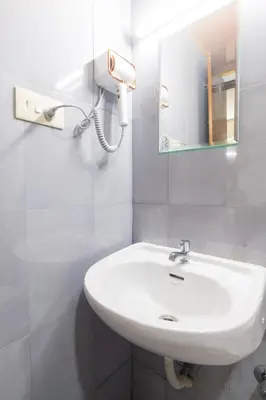 a bathroom with a white sink and a mirror at Sancta Maria Airport Suites in Nedumbassery